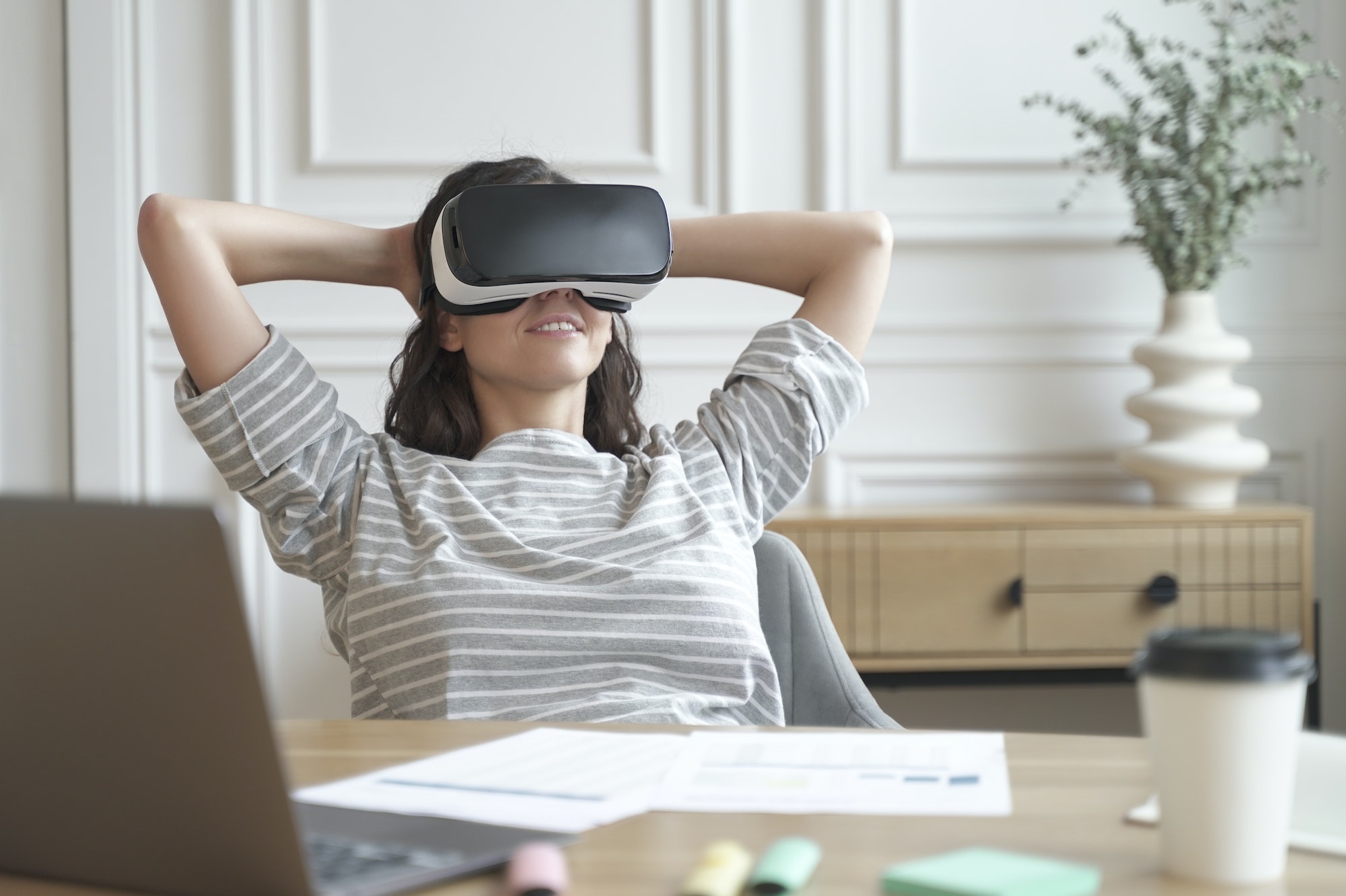 Relaxed young woman office worker in VR headset or helmet watching in 360 degrees video or movie